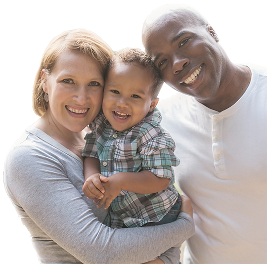 A smiling family of three, including two adults and a child, poses for the camera with affectionate expressions.